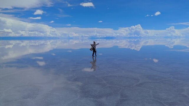A solitary figure traverses the expansive Salar de Uyuni in Bolivia, captured under a clear midday sky