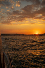 Beautiful glowing sunset on the European side of Istanbul, Turkey from Bosphorus toward Karakoy and Eminonu, with the silhouettes of Galata Tower and Suleymaniye Mosque against burning sky