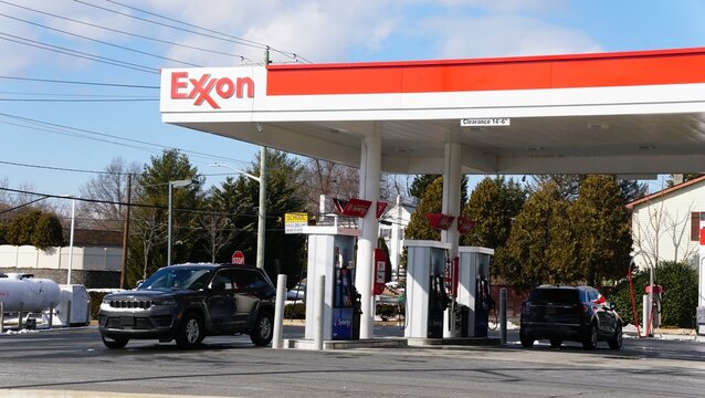 Wilmington, Delaware, U.S - Jan 19, 2026 - A grey Jeep Cherooke sits at an Exxon fuel pump under a white and red canopy on a clear day.