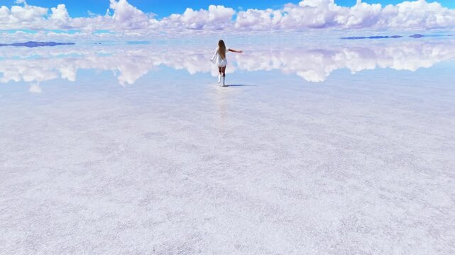 A woman running across the expansive Salar de Uyuni salt flats in Bolivia, capturing the serene beauty of the landscape 