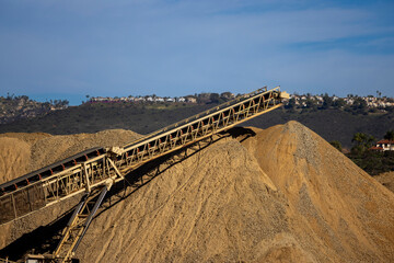 A conveyor machine and a large mound of dirt and gravel at a construction site