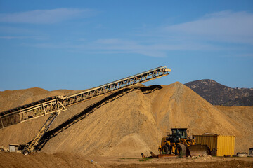 A conveyor machine and a large mound of dirt and gravel at a construction site