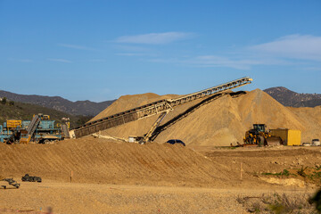 A conveyor machine and a large mound of dirt and gravel at a construction site