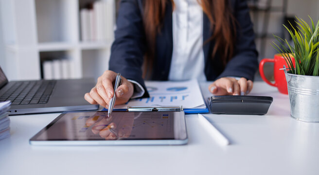 Closeup of business woman analyzing financial reports and calculating data at office desk
