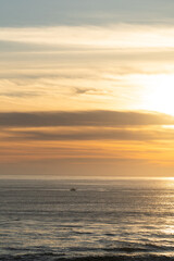 Fototapeta premium boat driving out to sea with sunrise over the ocean