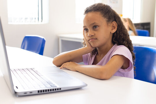 African American child in light purple T-shirt using open silver laptop at school lab, copy space