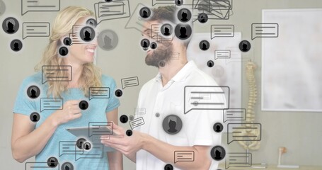 Discussing clinician patient viewing tablet in clinic light-blue top white-polo spine chat icons