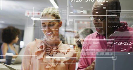 Reviewing laptop screen in open office, pair wearing pink shirts and glasses viewing HUD overlays