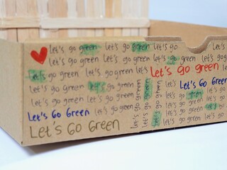 Recycled cardboard box with handwritten go green slogans and heart symbols