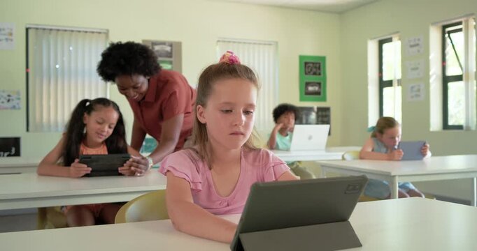 Diverse class with teacher approaching desk helping front-center youth girl tapping tablet, smiling