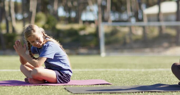 Diverse children clapping, camera panning, twisting, bowing on purple  and  black mats on turf for y