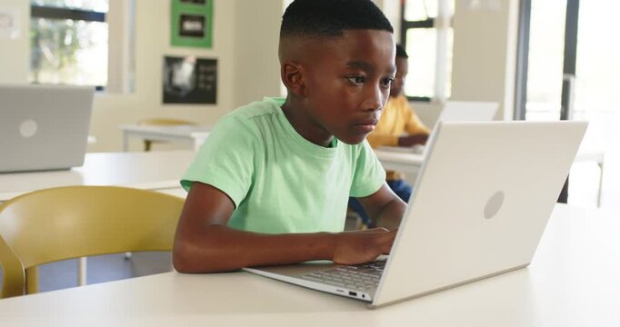 African American boy child sitting in mint shirt at white laptop, celebrating receiving feedback