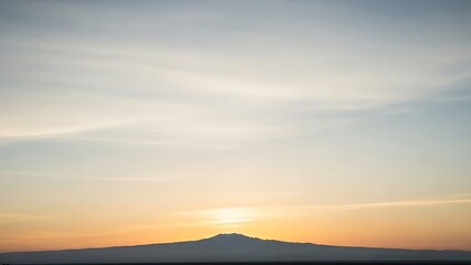 Obraz premium Serene sunrise paints the sky above distant mountain peaks with a beautiful blend of soft, tranquil morning colors, an awe-inspiring vista