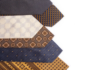 Assortment of men's neckties with different patterns isolated on a white background. Fashion accessories arranged diagonally with ample copy space for design.