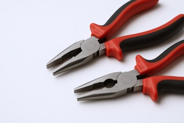 Obraz premium Pair of Combination Pliers with Red and Black Handles Isolated on a Clean White Surface