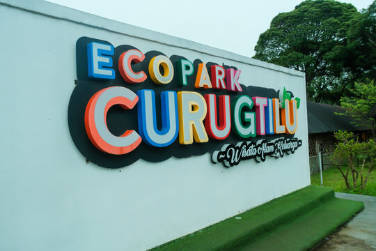 Bandung-Indonesia, 9th January, 2026 - Colorful sign Eco Park Curug Tilu on a white wall at an outdoor nature park entrance with green trees in background.