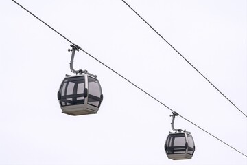 Two Modern Gondola Lifts Ascending, Suspended Against a Bright Sky, Showcasing Tourism and Transportation