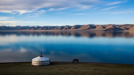 Serene mountain lake reflecting the blue sky, featuring a traditional yurt and a horse on the shore.