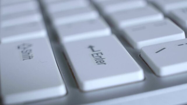 Detailed macro view of a finger activating the enter key on a contemporary computer keyboard for command execution