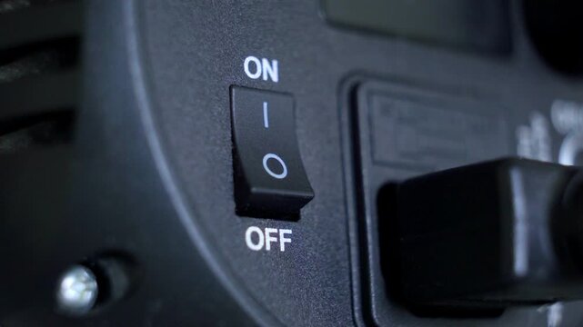 Close up view of a human hand operating an on off power switch on a continuous studio illumination device, controlling its function