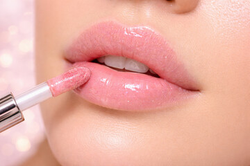 Macro close up of soft lips with transparent pink lip gloss and applicator. Lip care, beauty cosmetics, natural look, glossy texture, skincare and fresh makeup style.