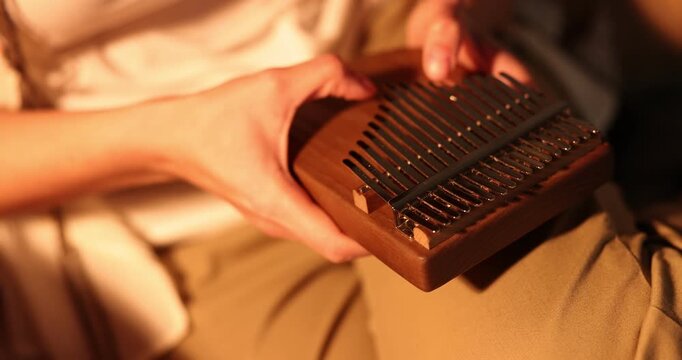 Woman playing kalimba at home, closeup. Musical instrument