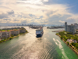 Big passenger cruise liner ship departing at main channel in Miami harbor near South Beach high luxurious hotels and apartment buildings.