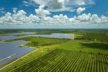 Aerial view of sustainable electric power plant between agricultural farm fields with solar photovoltaic panels for producing clean electrical energy. Renewable electricity with zero emission concept