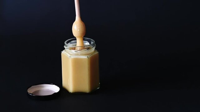 Honey Dipper Drizzling Creamed Honey, black background