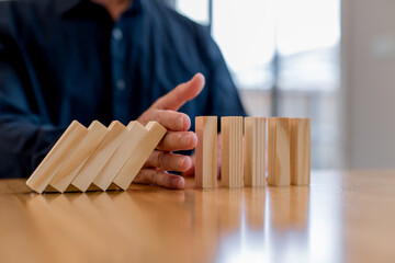 risk management and business protection concept. Preventing failure, stability control, crisis prevention, strategic planning and leadership decision making,Hand stopping falling wooden blocks