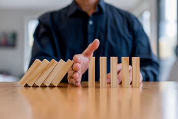 risk management and business protection concept. Preventing failure, stability control, crisis prevention, strategic planning and leadership decision making,Hand stopping falling wooden blocks