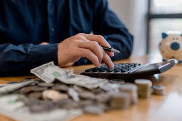 Man calculating personal budget with calculator, coins and dollar banknotes on table. Financial planning, saving money, expense control, household finance management and economic responsibility concep