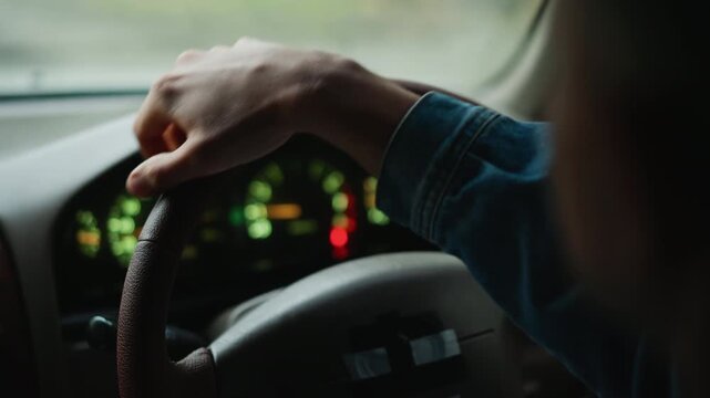 daytime denim hand firm on wheel, driver adjusting grip while scanning road, clear dashboard indicators and green countryside outside, steady pace, casual roadtrip vibe and navigation focus, ideal