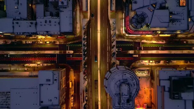 bird's eye view Berlin city street seen from above at night during winter. Bright streetlights illuminating snow covered rooftops and busy roads with traffic. Majestic aerial view ascending raise up