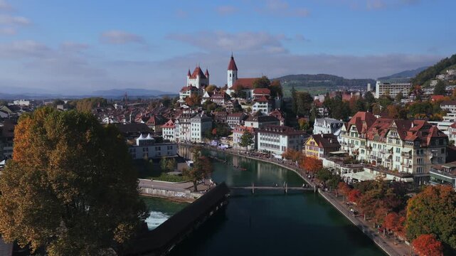 Schloss Thun Flusswelle Aare River sunny blue sky clouds aerial drone Autumn Fall Thun Castle Thunersee Switzerland Schweiz Europe yellow trees outdoor park buildings Bernese Oberland backwards pan up