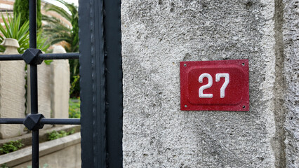 Number 27 on a stone wall near a gate
