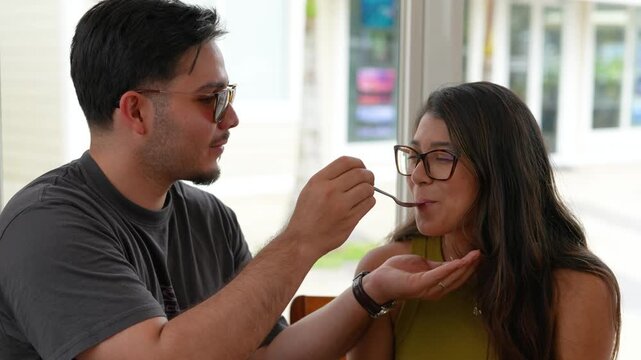 Young couple sharing dessert and smiling together inside cozy cafe