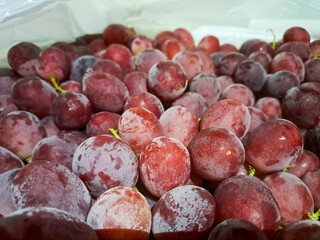 Piles of delicious fresh juicy seedless red grapes background in local city fruit market	
