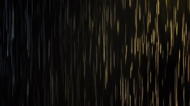 Blurry rain drops falling on a dark background with golden highlights.