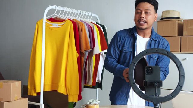 Energetic live seller presenting hats to virtual audience via mobile phone setup in studio
