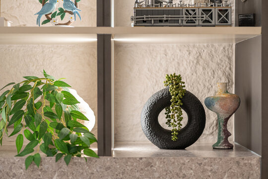 Modern shelf decor featuring a Senecio rowleyanus plant in a black circular textured vase.