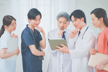 タブレットを見ながら議論する多世代の医療スタッフ