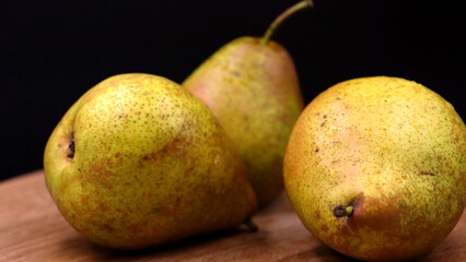 Realistic fresh pears on wood, dark background