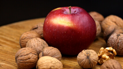 Fresh red apple and walnuts on rustic wooden board