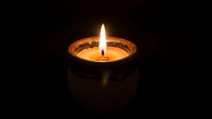Lit candle in ceramic holder on dark background flame burning candle
