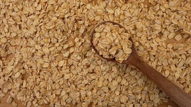 Dry uncooked oat flakes top view. Rolled oats in a wooden spoon. 