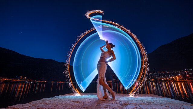 Lightpainting auf einem Steg mit einer sch&ouml;nen Frau im wei&szlig;en Kleid