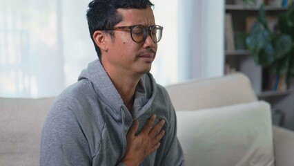 Asian Man Suffering from Chest Pain and Holding His Heart Due to Health Problems.
