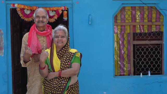 senior indian farmer couple showing voting sign 