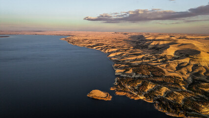 Tishrin Dam in Syria. A massive water dam in the desert. High-angle drone shot showing a giant dam structure holding back turquoise river water amid an arid desert landscape, used for water management